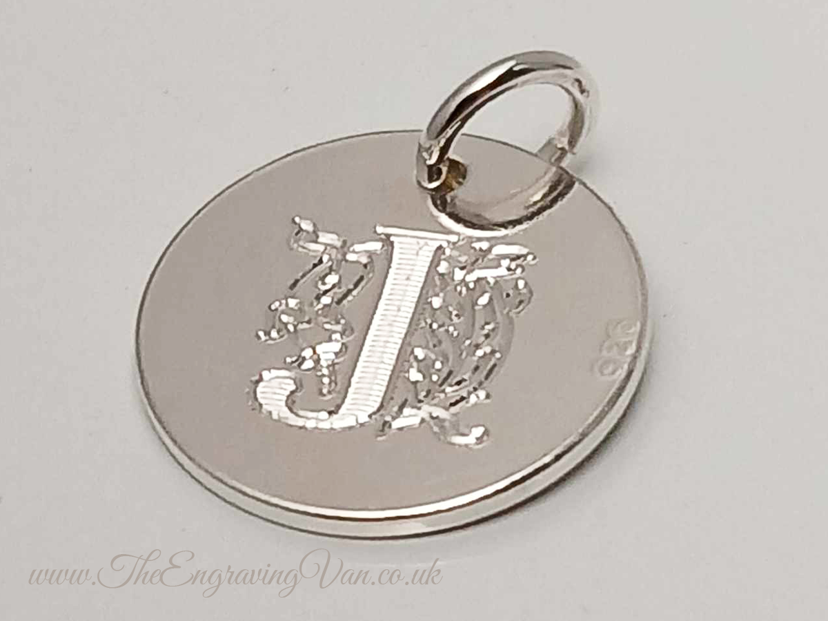 Sterling Silver Disk Charm engraved with a Decorative Monogram Initial on one side.